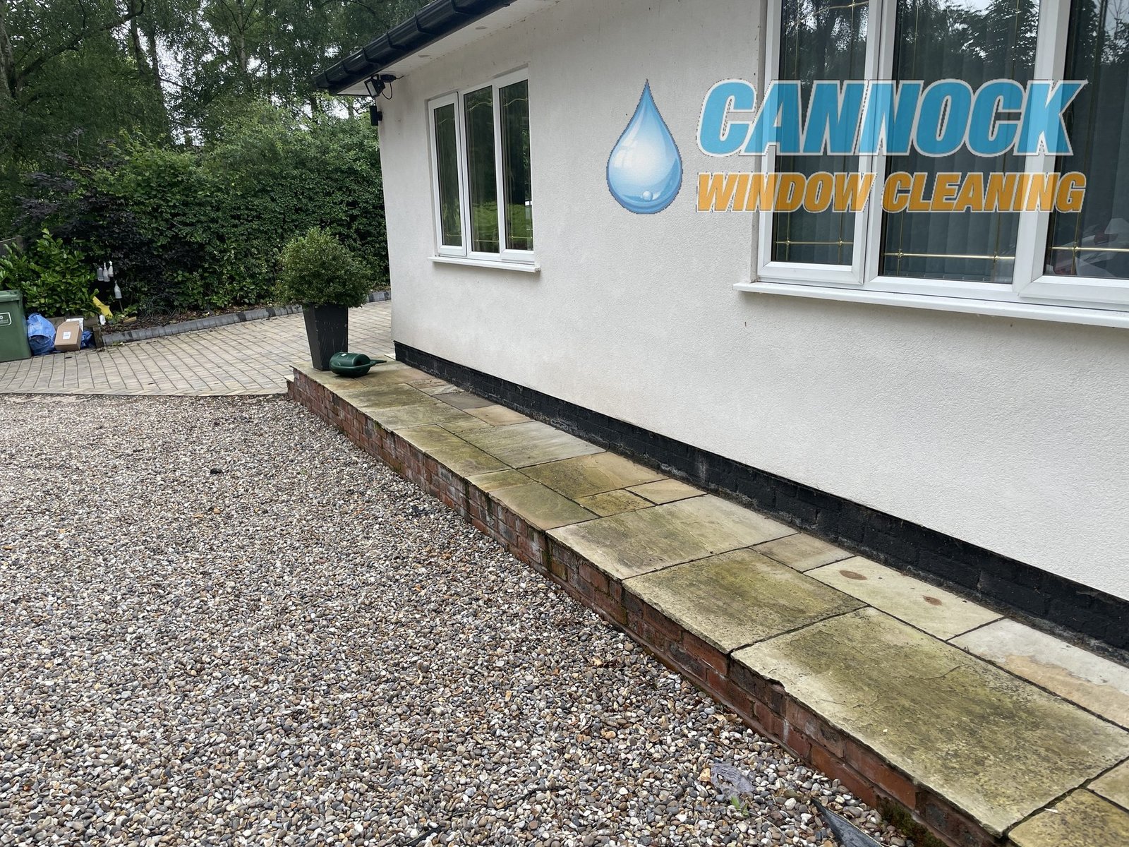 Sandstone path along a house green with algae before cleaning